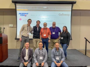 Galloway's team poses with Murphy USA's team on stage at a conference.